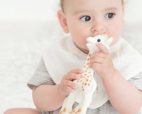 Vol Verwachting - Baby met slabbetje en bijt speelgoed giraffe