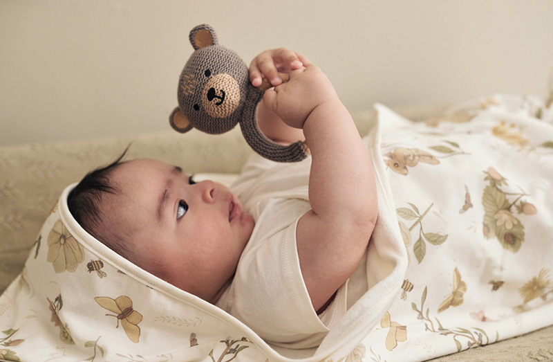 Vol Verwachting - Baby houd bijtring vast terwijl ingewikkeld in wikkeldoek