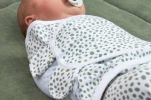 Vol Verwachting - Baby die is ingebakerd in een wit met groen gestipte wikkeldoek