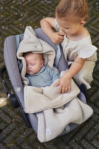 Vol Verwachting - Twee kinderen waarvan de baby in een voetenzak slaapt