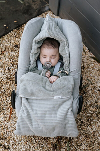 Vol Verwachting - Slapende baby in autozitje met een voetenzak dat buiten staat